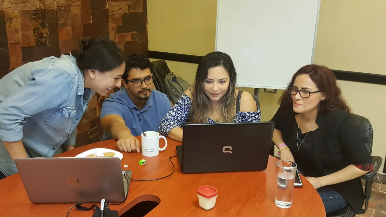 Cuatro profesionales trabajando juntos con laptops en una sesion de Escala University