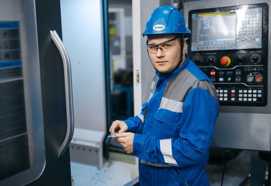 Técnico con casco operando una máquina en planta
