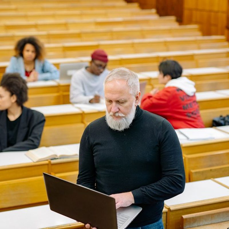 Adulto estudiando con su laptop en un aula universitaria